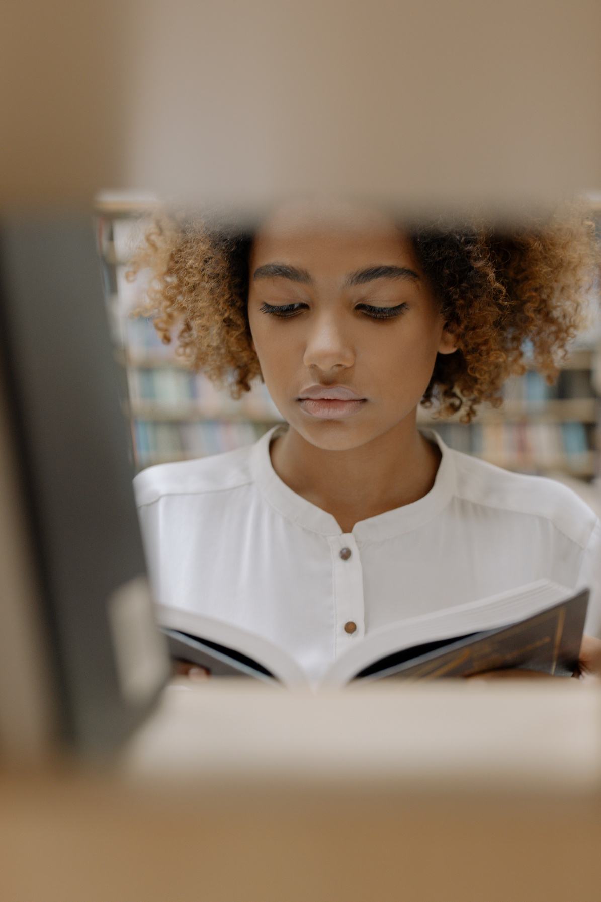 young person reading a book in a library